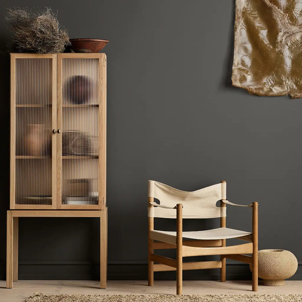 Wooden cabinet and chair against a dark gray wall with decorative elements.