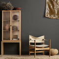 Wooden cabinet and chair against a dark gray wall with decorative elements.