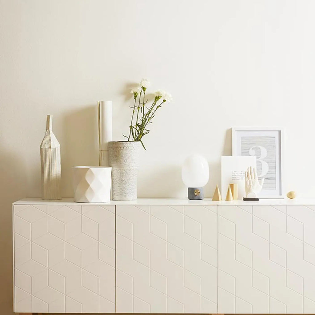 White sideboard with decorative items against a plain wall