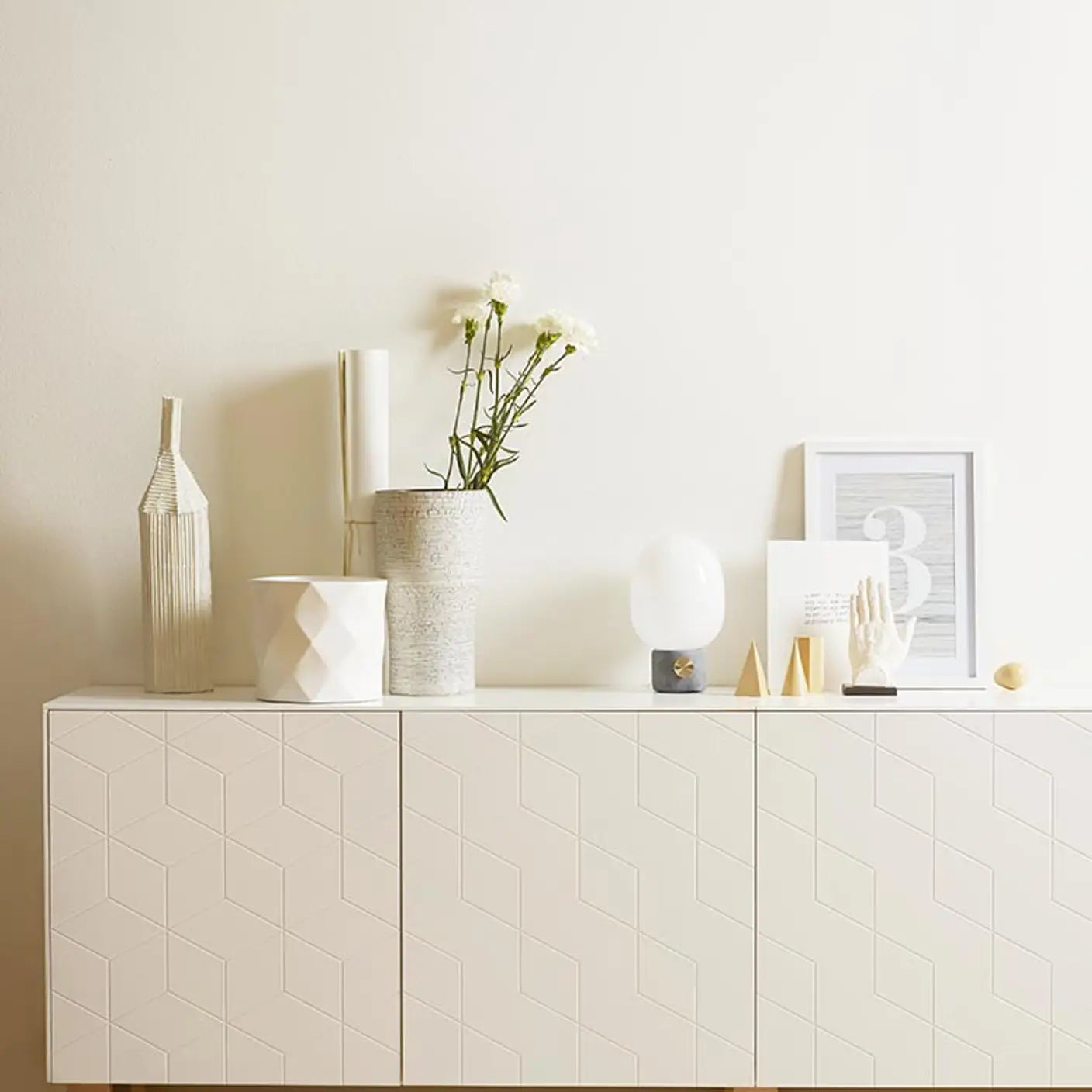 White sideboard with decorative items against a plain wall