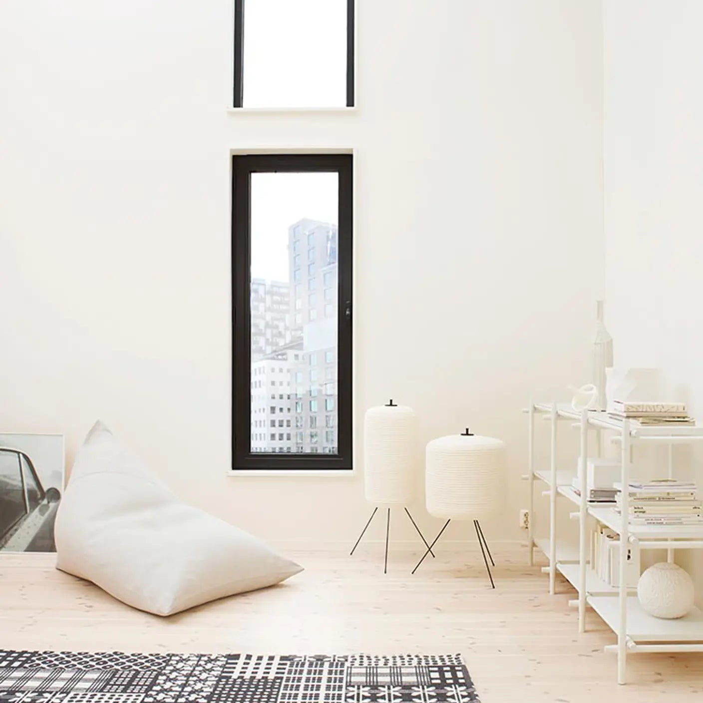 Modern interior with a rug, pillows, and a window view of a cityscape.