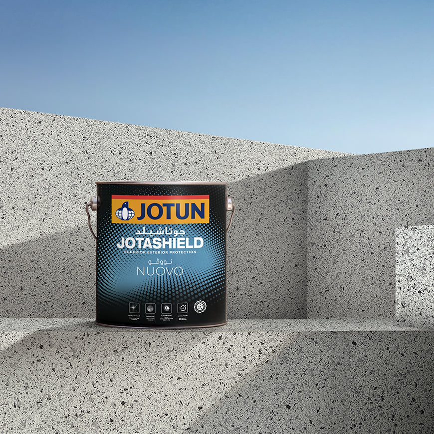 Jotun Jotashield paint can on a concrete surface with a clear blue sky.